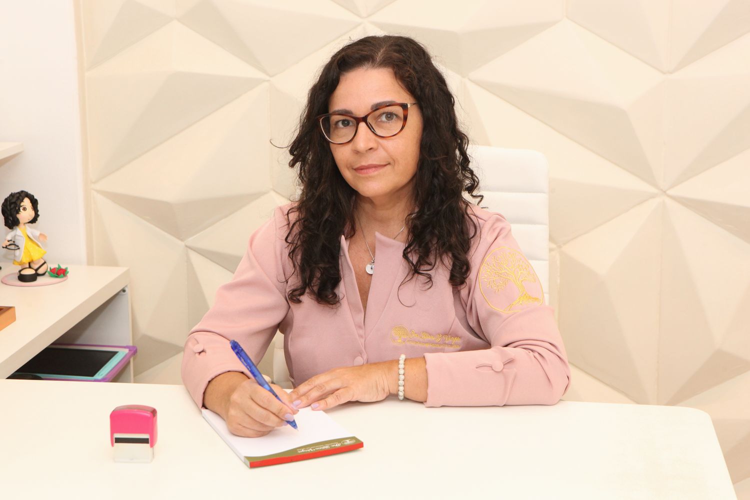 Dra. Letícia escrevendo um plano à mesa do consultório