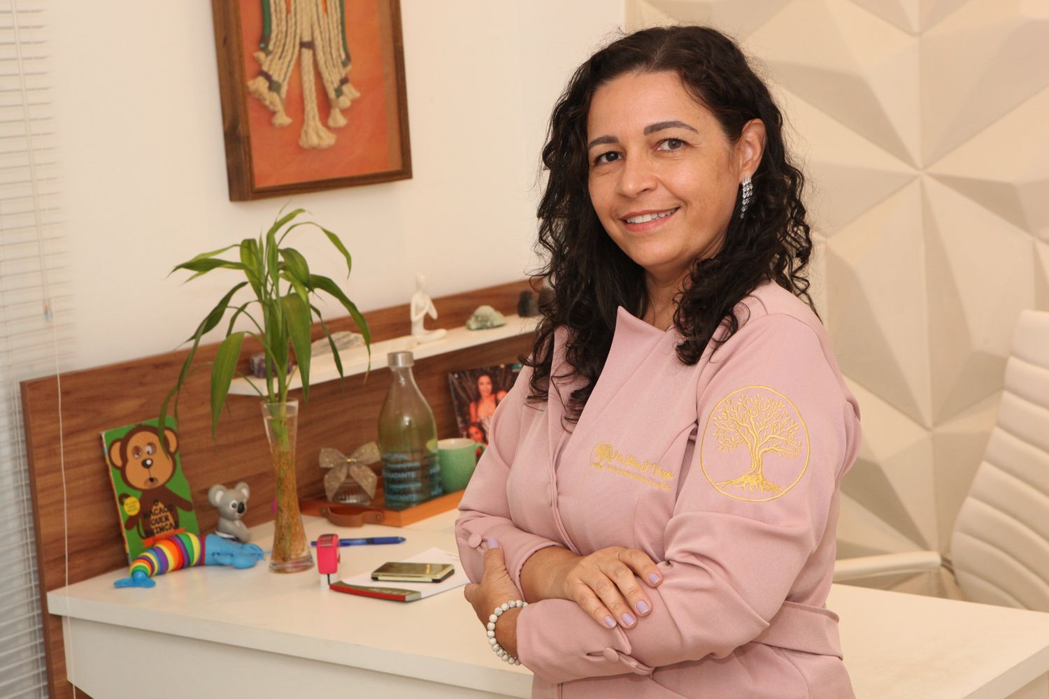 Dra. Letícia Barbosa Vargas de braços cruzados, sorrindo, no consultório